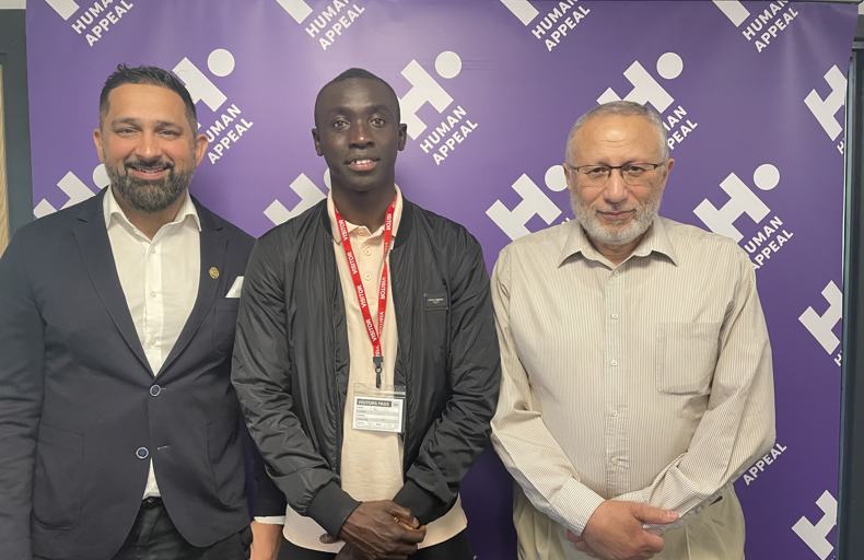 Papisse Cisse standing with Human Appeal's CEO, Dr. Mohamed Ashmawey, and Fundraising Director, Zaheer Khan