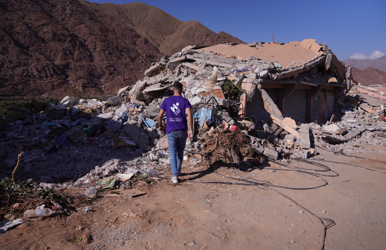 Human Appeal staff member looking at a damaged building